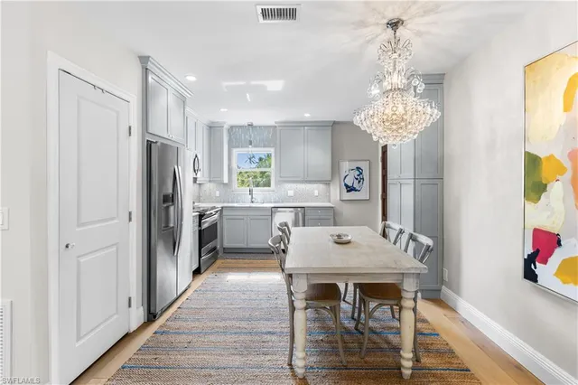 a kitchen with stainless steel appliances a dining table chairs and chandelier