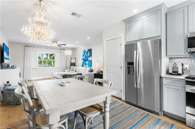 a kitchen with stainless steel appliances a table chairs refrigerator and microwave