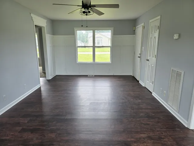 an empty room with wooden floor fan and windows