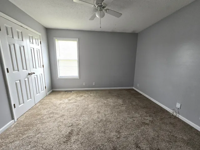 an empty room with a window and a ceiling fan