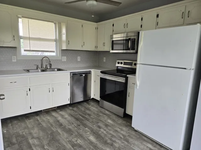 a kitchen with granite countertop white cabinets and stainless steel appliances