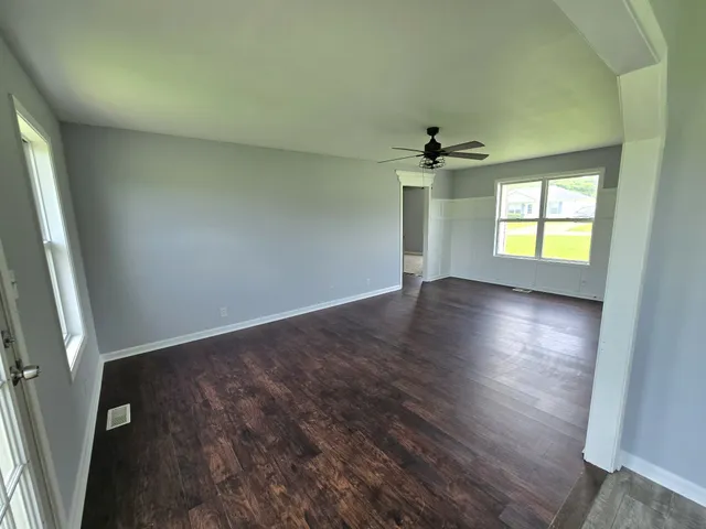 an empty room with windows and a ceiling fan