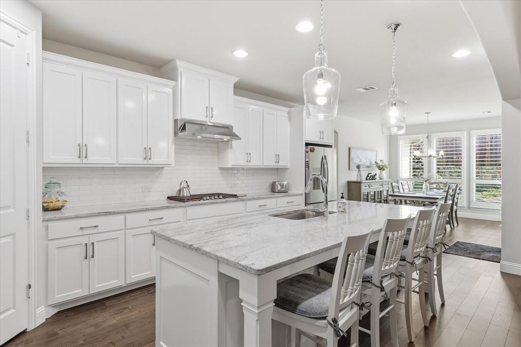 9708 Surveyor Road Oak Point, TX 75068 - Photo 6 of 34 Contemporary kitchen featuring white shaker cabinetry, light-toned countertops, a subway tile backsplash, and stainless steel appliances