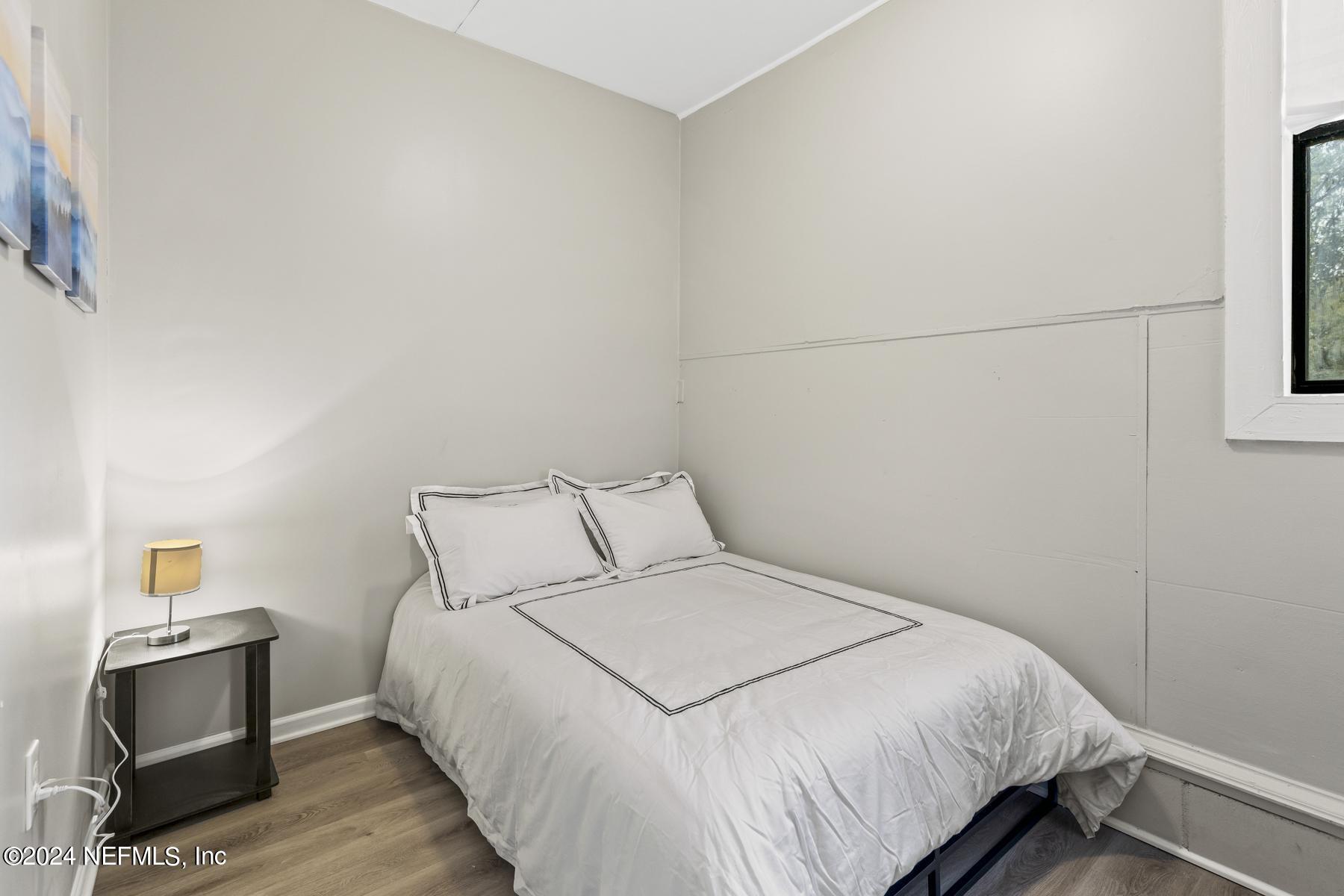 7142 Richardson Road Jacksonville, FL 32209 - Photo 2 of 10 a bedroom with a bed and wooden floor