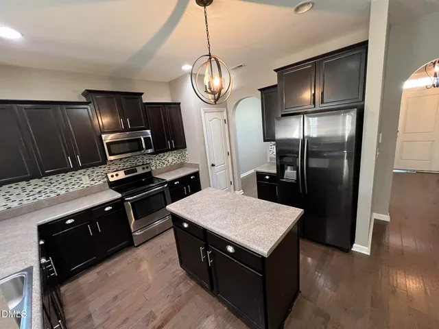 a kitchen with stainless steel appliances granite countertop a refrigerator a stove and a sink