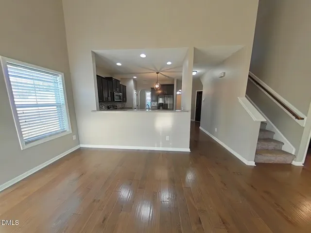 a view of a living room with wooden floors and kitchen view
