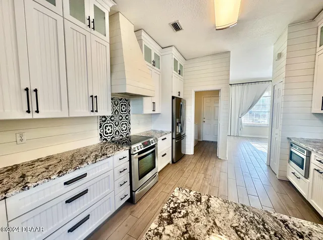 a kitchen with granite countertop white cabinets and wooden floor