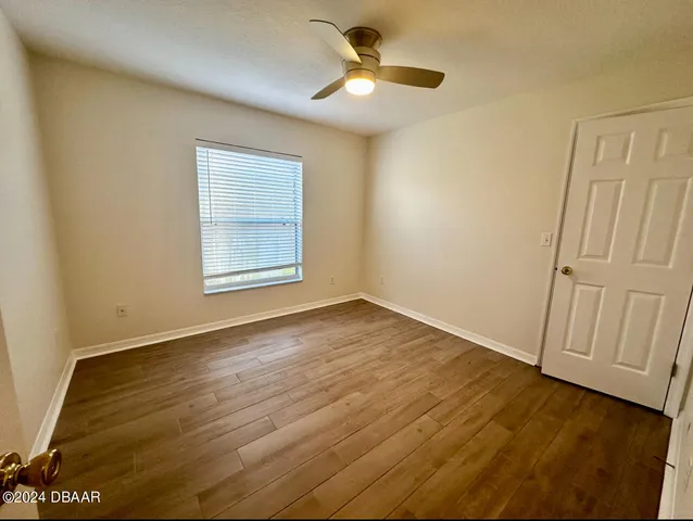 an empty room with wooden floor fan and windows