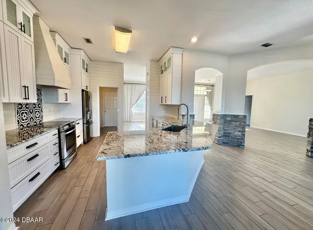 a large kitchen with stainless steel appliances granite countertop a lot of counter space and wooden floors