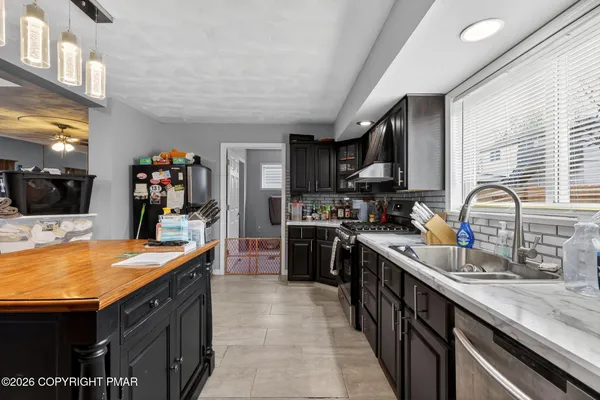 a room with stainless steel appliances kitchen island granite countertop a refrigerator and a stove top oven