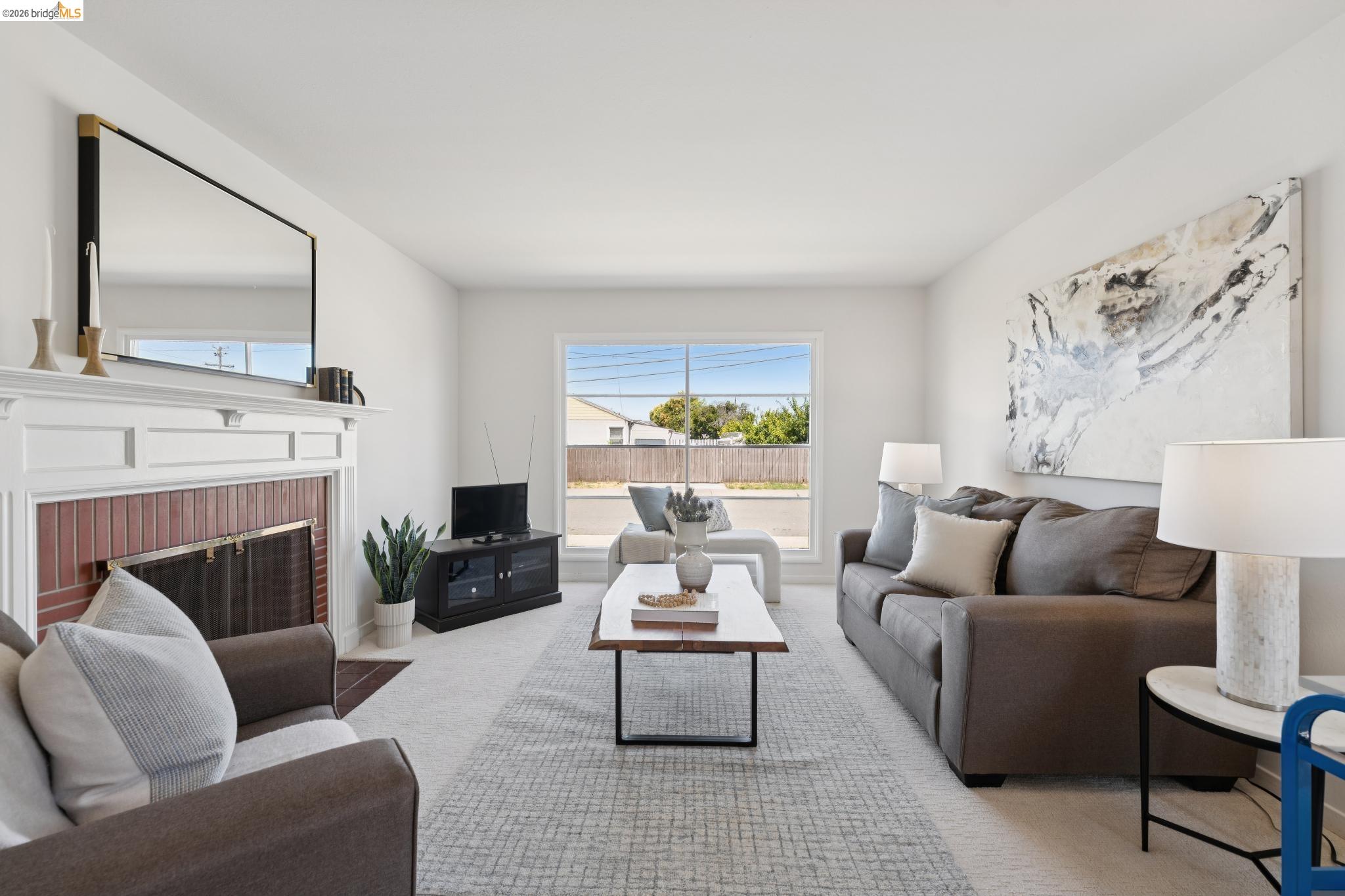 15162 Inverness Street San Leandro, CA 94579 - Photo 4 of 25 Bright living area featuring a white mantel fireplace with brick surround, wall-to-wall carpeting, and a large window providing outdoor light
