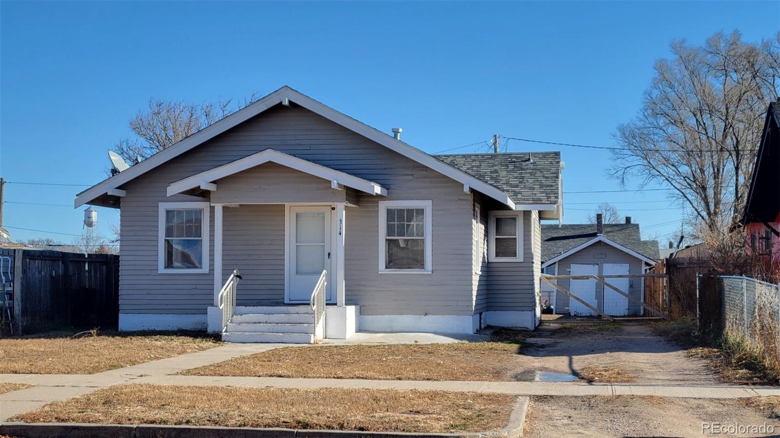 a view of a house with wooden fence next to a yard