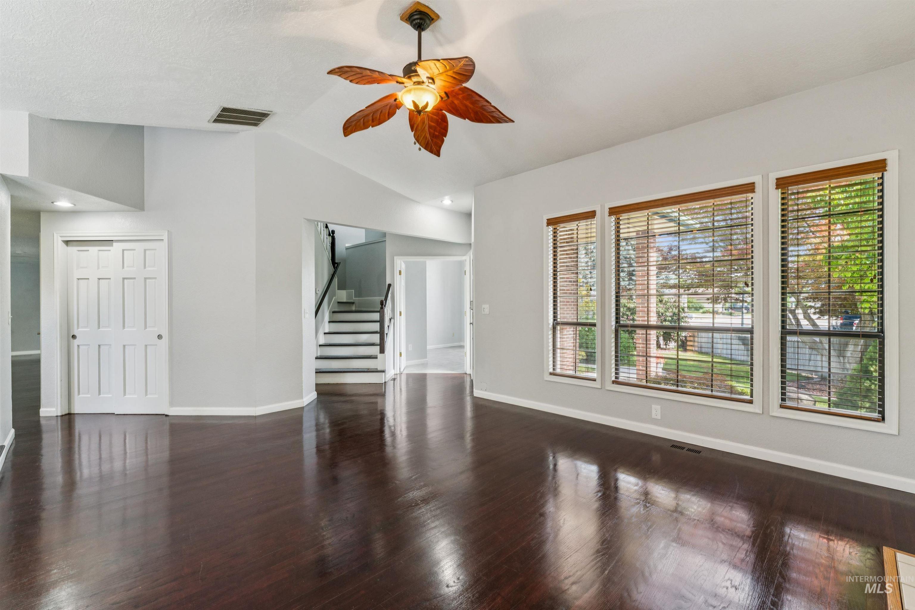 9831 West Ripley Street Boise, ID 83704 - Photo 5 of 47 Spacious living area featuring dark wood-finish flooring, a white mantel fireplace with tile surround, and vaulted ceilings with a ceiling fan