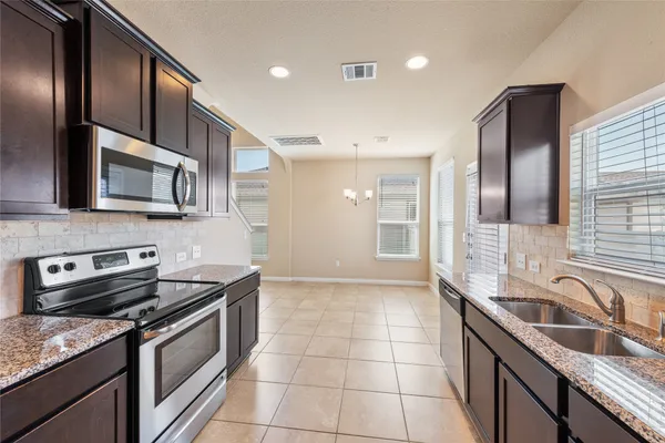 a kitchen with granite countertop a sink stainless steel appliances and cabinets
