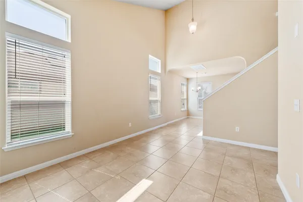 a view of an empty room with window and chandelier fan