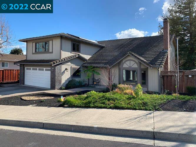 a front view of a house with garage and plants