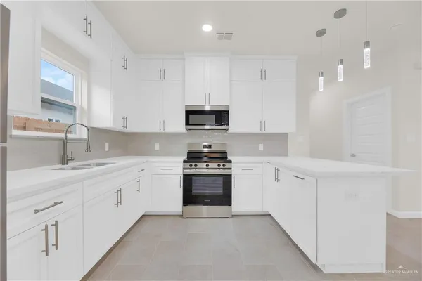 a kitchen with granite countertop white cabinets and stainless steel appliances