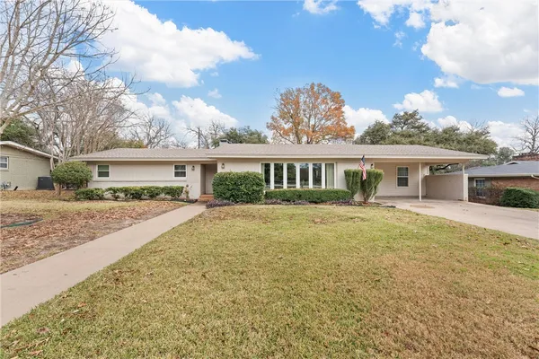 a front view of house with yard and trees in the background