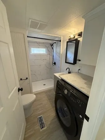 a bathroom with a sink a toilet a mirror and shower