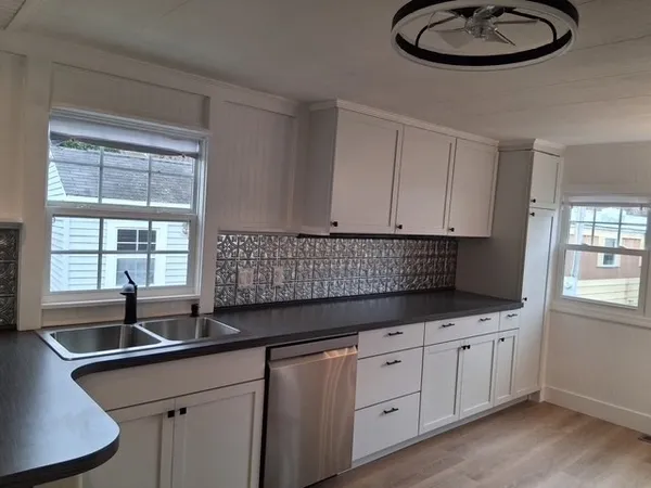 a kitchen with granite countertop a sink a window and cabinets