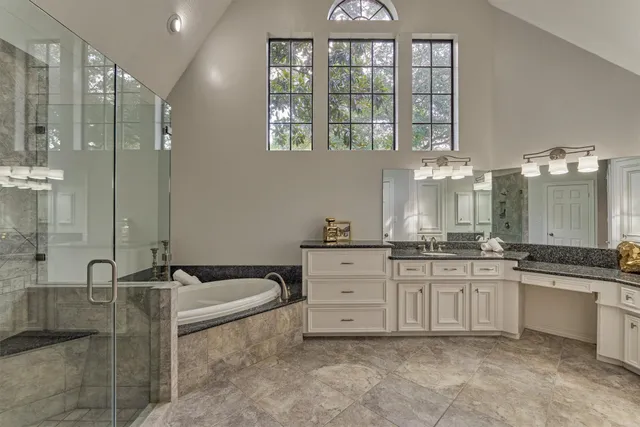 a spacious bathroom with a granite countertop tub sink and mirror