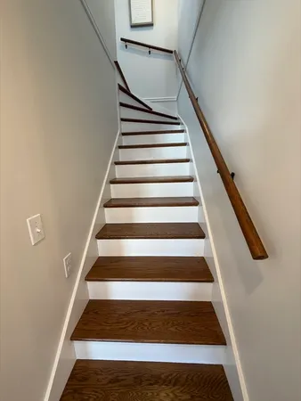 a view of staircase with wooden floor and white walls