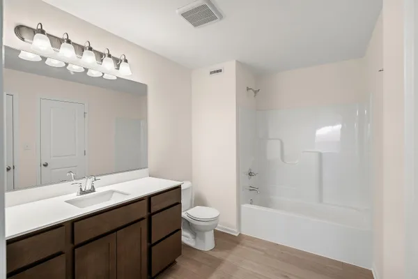 a bathroom with a sink a toilet a mirror and shower