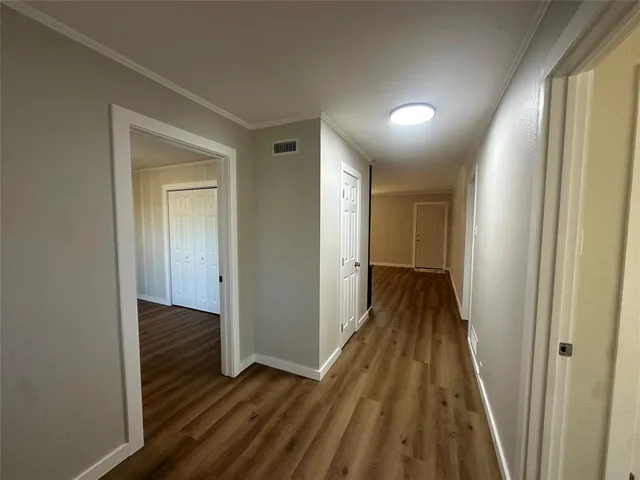 a view of a hallway with wooden floor and a bathroom