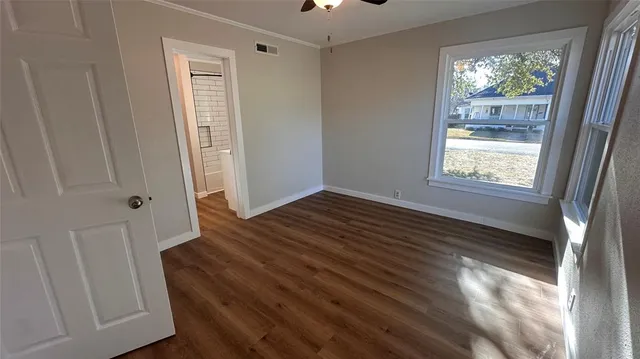 a view of an empty room with wooden floor and a window