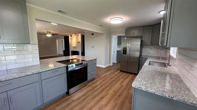 a large kitchen with granite countertop a large counter top a sink stainless steel appliances and cabinets