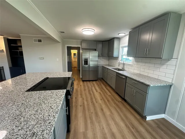 a large kitchen with a lot of counter space and wooden floor