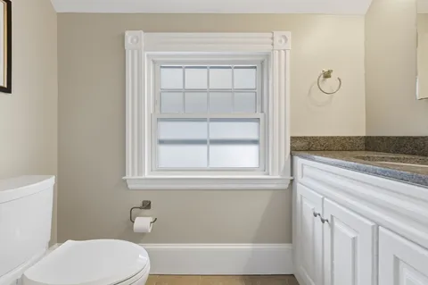 a bathroom with a granite countertop toilet and a sink