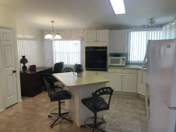 a kitchen with a refrigerator a stove a sink dishwasher with a dining table and chairs