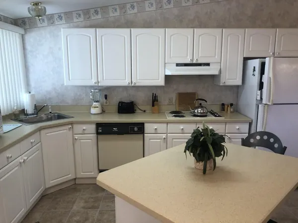 a kitchen with stainless steel appliances a sink a stove a refrigerator a white table and chairs