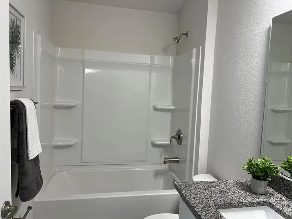 a bathroom with a granite countertop bathtub shower and toilet