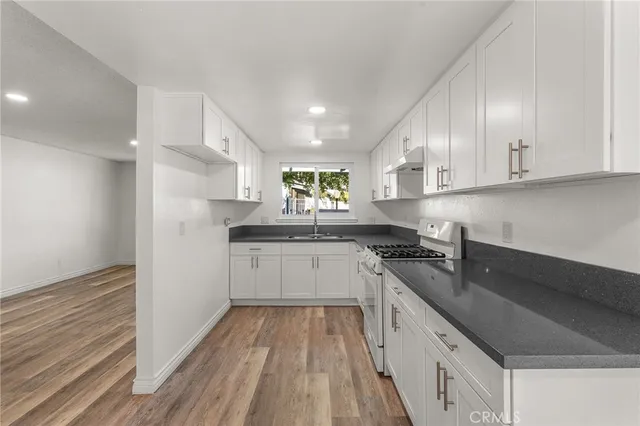 a kitchen with granite countertop a sink stainless steel appliances and cabinets