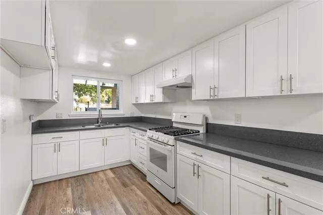 a kitchen with granite countertop white cabinets and white appliances