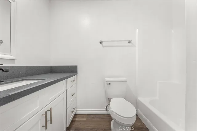 a bathroom with a granite countertop toilet and a sink