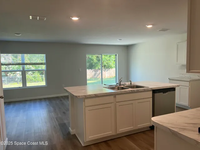 a view of an empty room with wooden floor and a sink