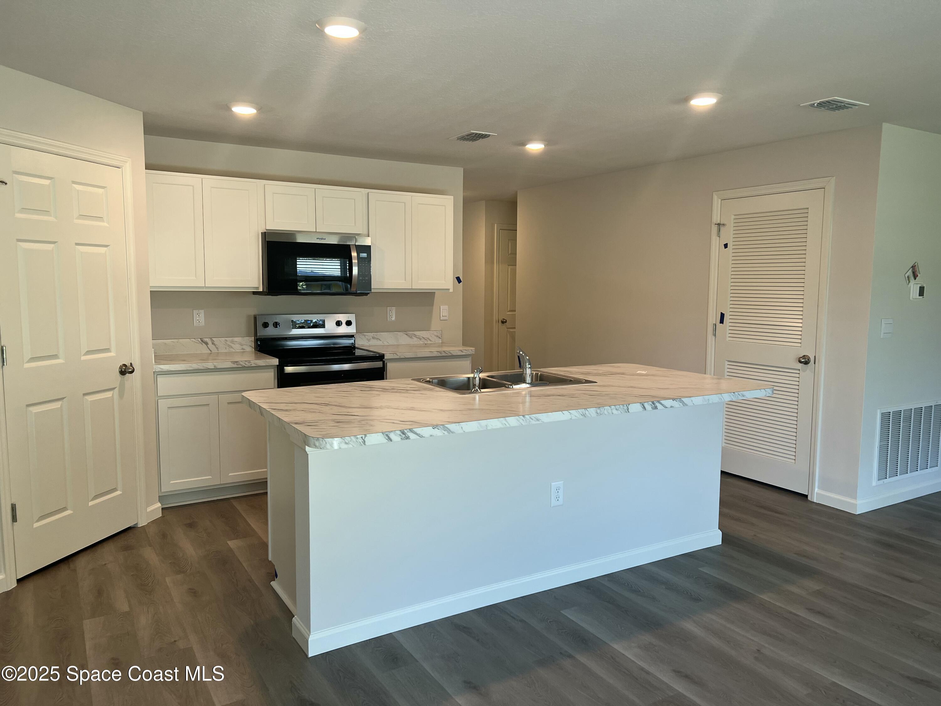 881 Hollahan Road Southeast Palm Bay, FL 32909 - Photo 13 of 21 a living room with stainless steel appliances kitchen island granite countertop a stove a sink a refrigerator and a microwave