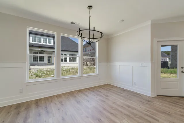 a view of an empty room with wooden floor and windows