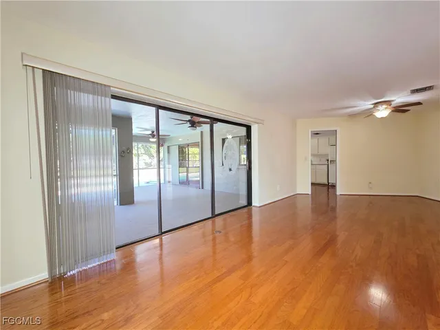 a view of an empty room with wooden floor and a window