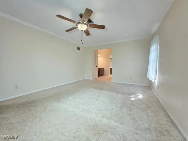 an empty room with a chandelier fan and windows