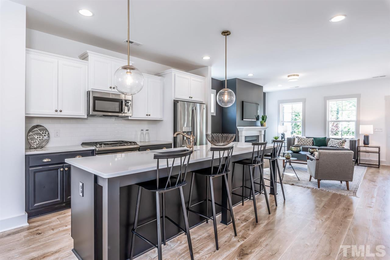 a kitchen with stainless steel appliances granite countertop a stove a refrigerator a microwave a dining table and chairs with wooden floor
