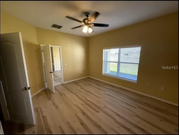 an empty room with wooden floor and a ceiling fan