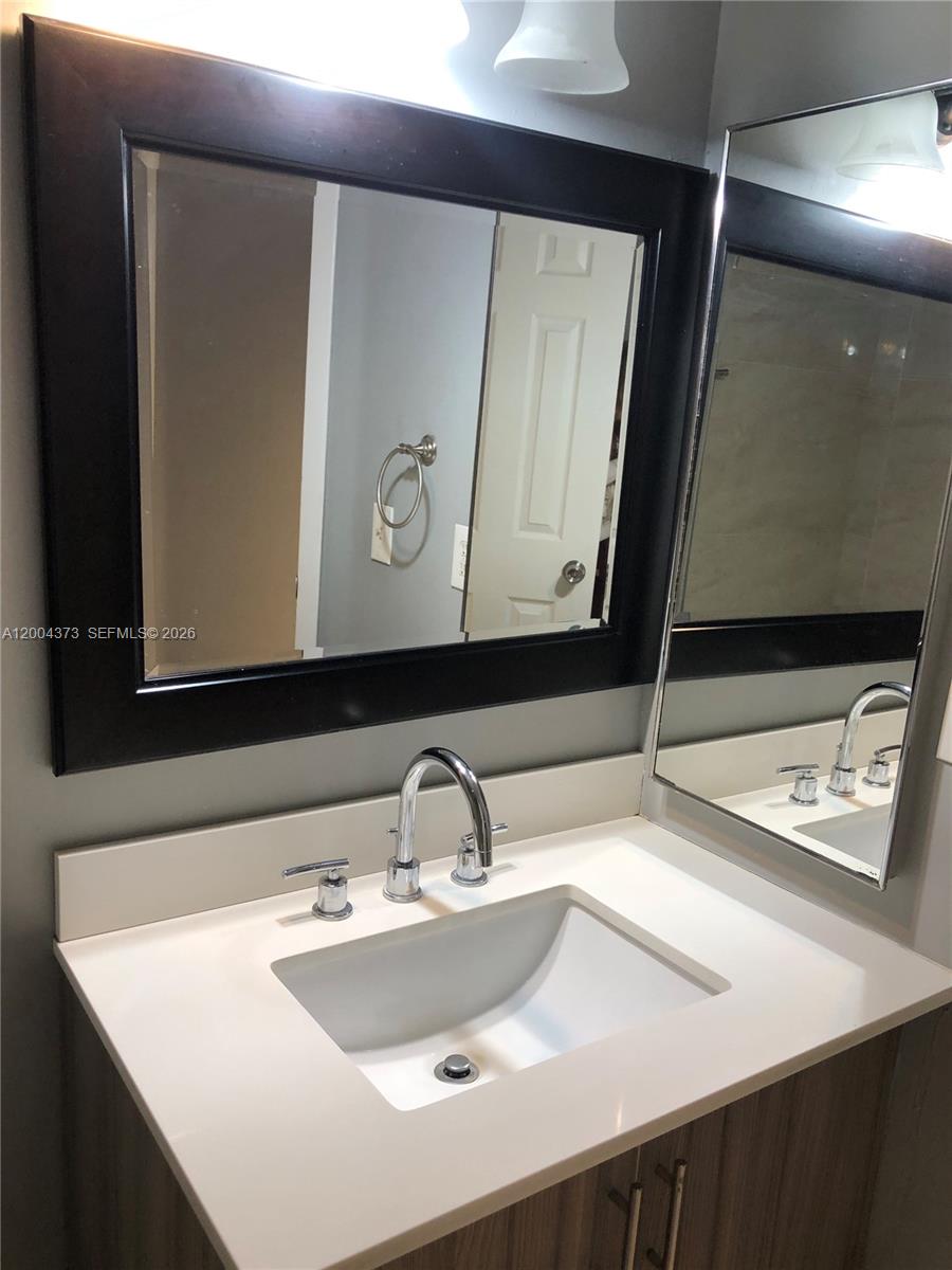 8761 Wiles Road, Unit 306 Coral Springs, FL 33067 - Photo 6 of 26 a bathroom with a sink and a mirror