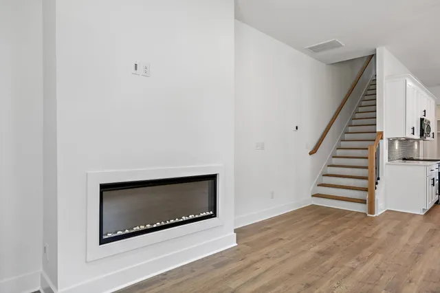 a view of a hallway with wooden floor and a bathroom