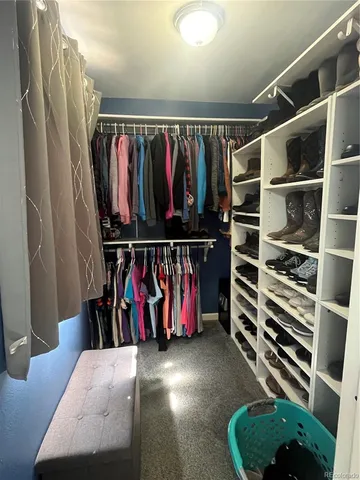 a view of walk in closet with clothes and shoes