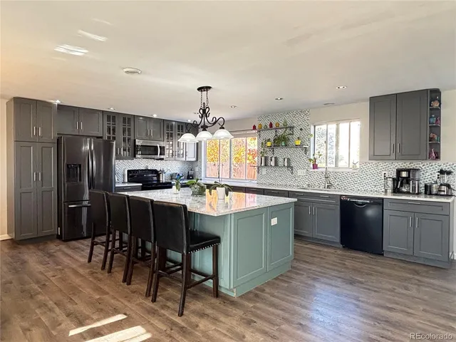 a kitchen with stainless steel appliances granite countertop a sink a stove a refrigerator cabinets and dining table