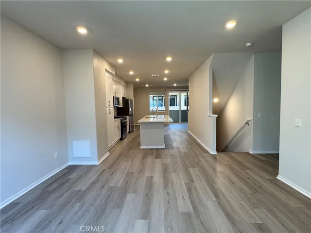 a view of a big room with wooden floor and a kitchen